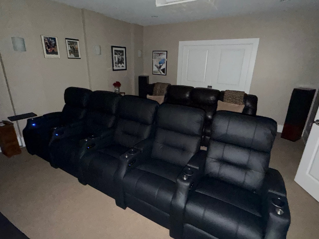 Black leather sectional theater seating with multiple reclining chairs arranged in a home entertainment room