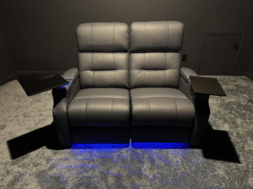 Two-seat gray leather power recliner with armrest tray tables and blue LED base lighting
