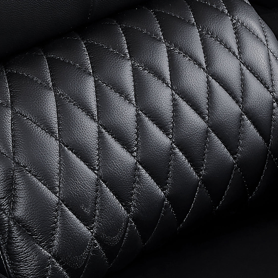 Close-up of premium top-grain leather upholstery with diamond stitching on black recliner