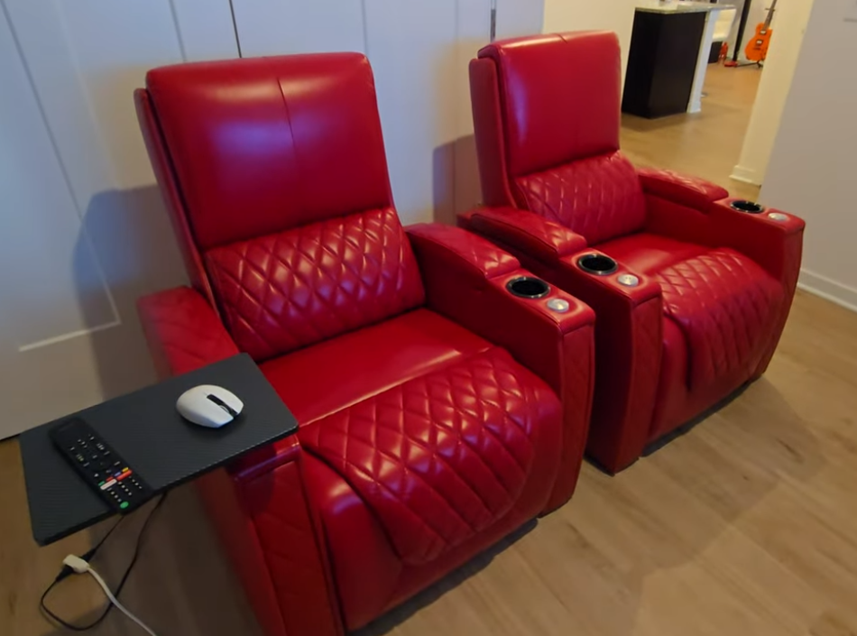 Two red leather power recliner chairs with quilted stitching and center console in a modern room